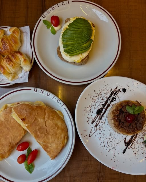 Mesa de desayuno con medialunas, tostada con palta y huevo, y un postre